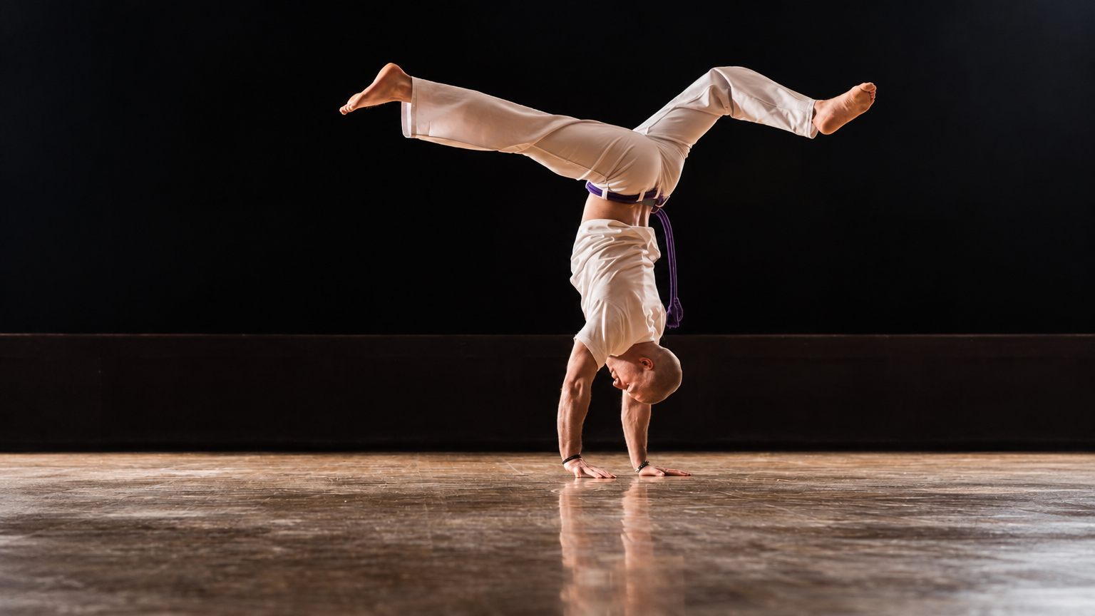 Praticante de capoeira em movimento de equilíbrio sobre as mãos